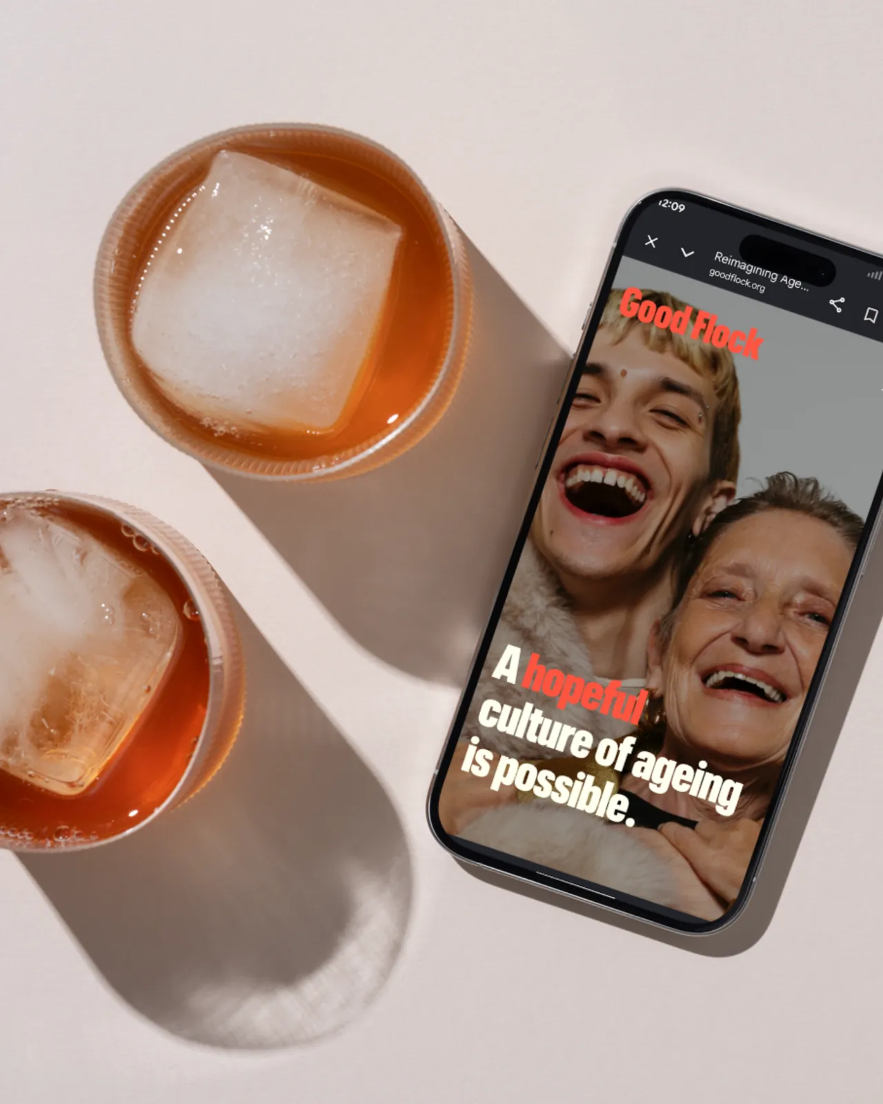 Good Flock mobile site on a phone beside iced drinks