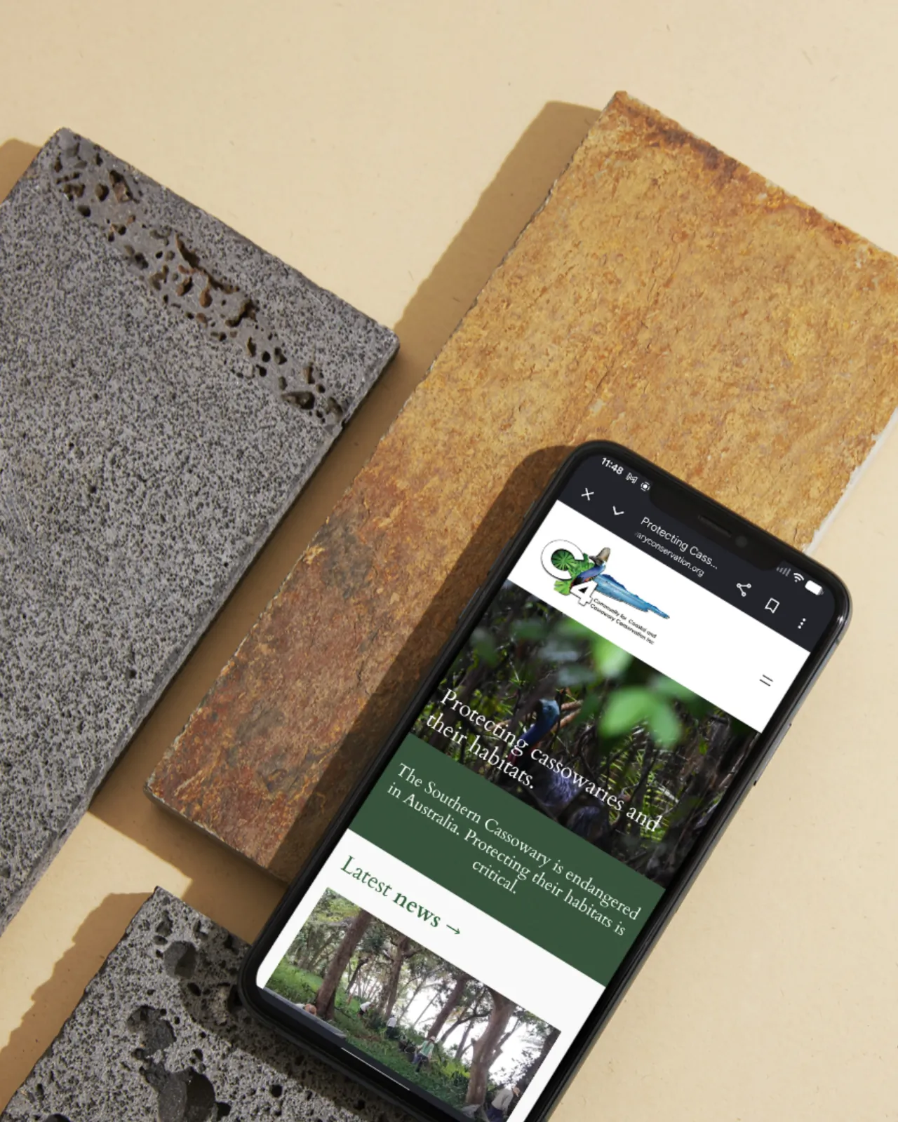 C4 conservation website on a phone over textured stone tiles
